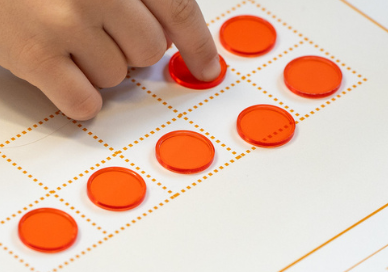 Child placing counters on a page